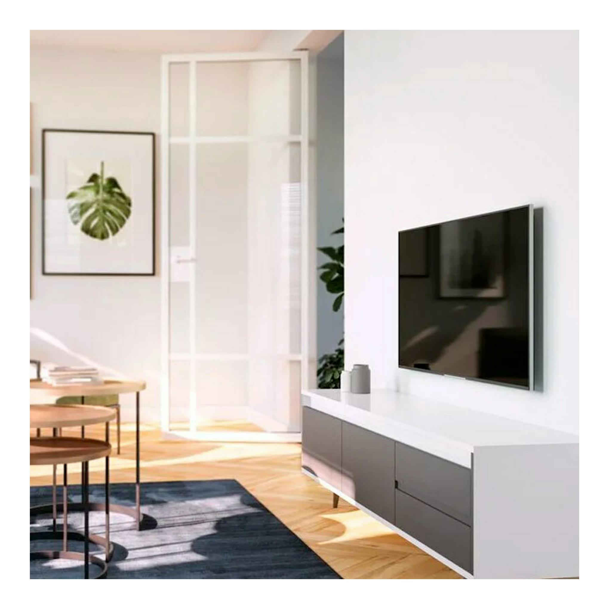 Soporte TV Vogels TVM 3203 con televisor montado en pared, vista lateral, en salón blanco.