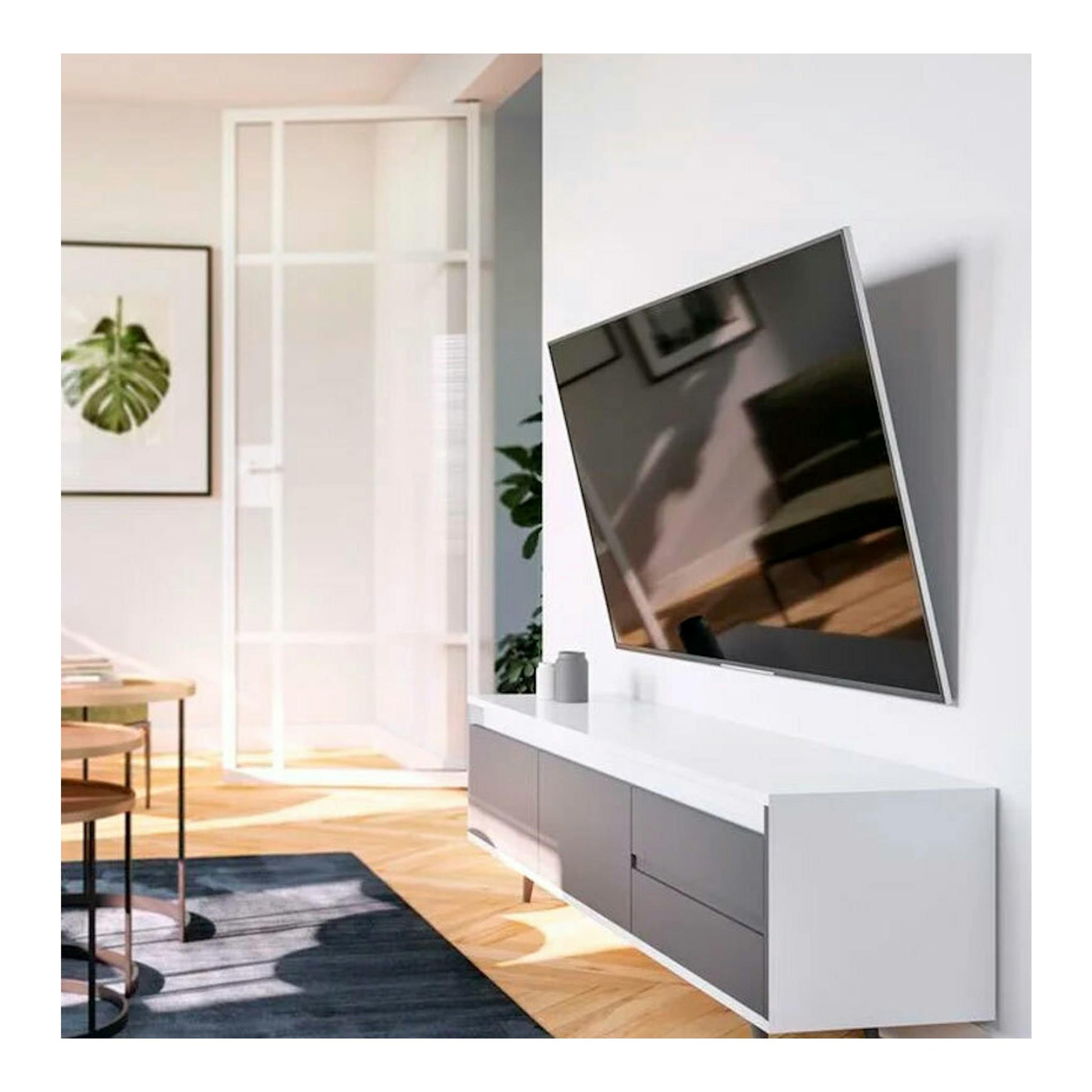Soporte TV Vogels TVM 3413 con televisor inclinado en pared blanca, vista lateral en salón moderno.
