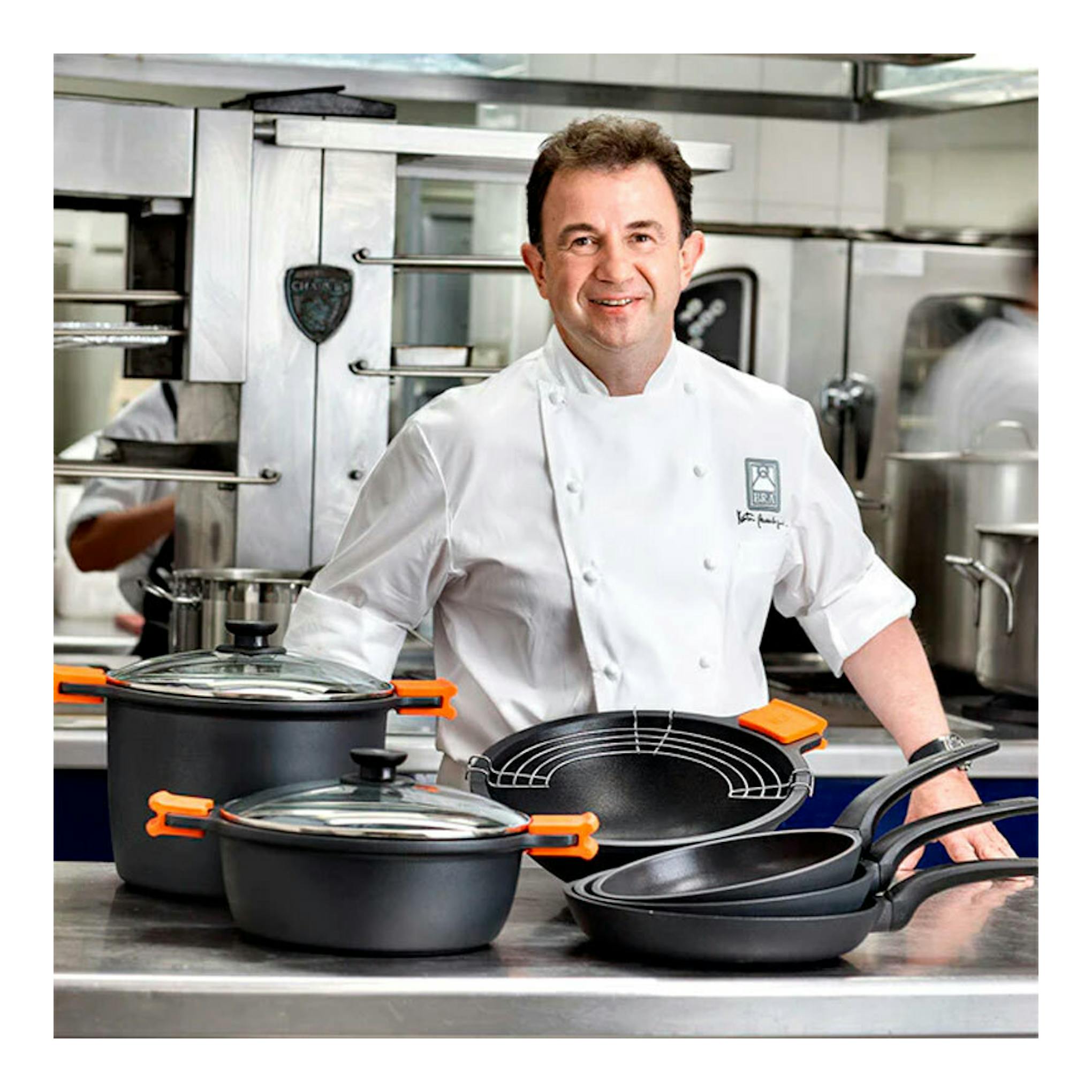 Chef junto a cacerola alta Bra Efficient negra con tapa de vidrio y sartenes, vista frontal.