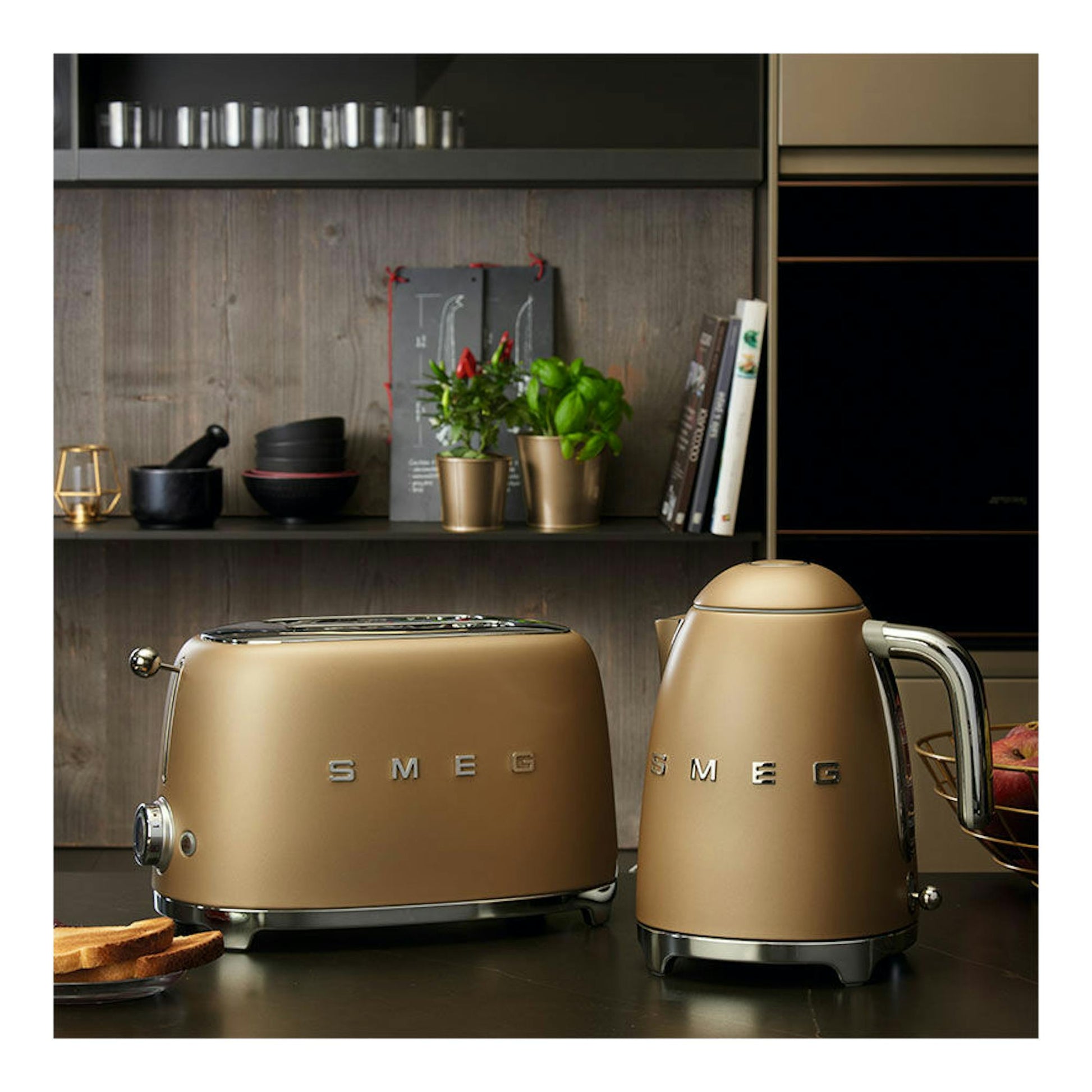 Tostador Smeg TSF01CHMEU oro mate, vista frontal sobre encimera, junto a una hervidora a juego.