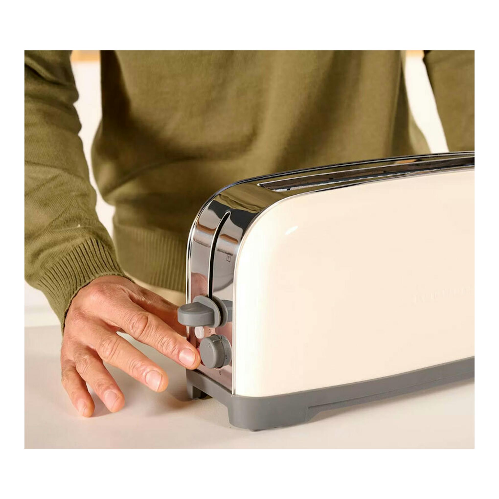 Tostador Taurus Vintage Single crema, vista lateral, con una mano ajustando el mando.
