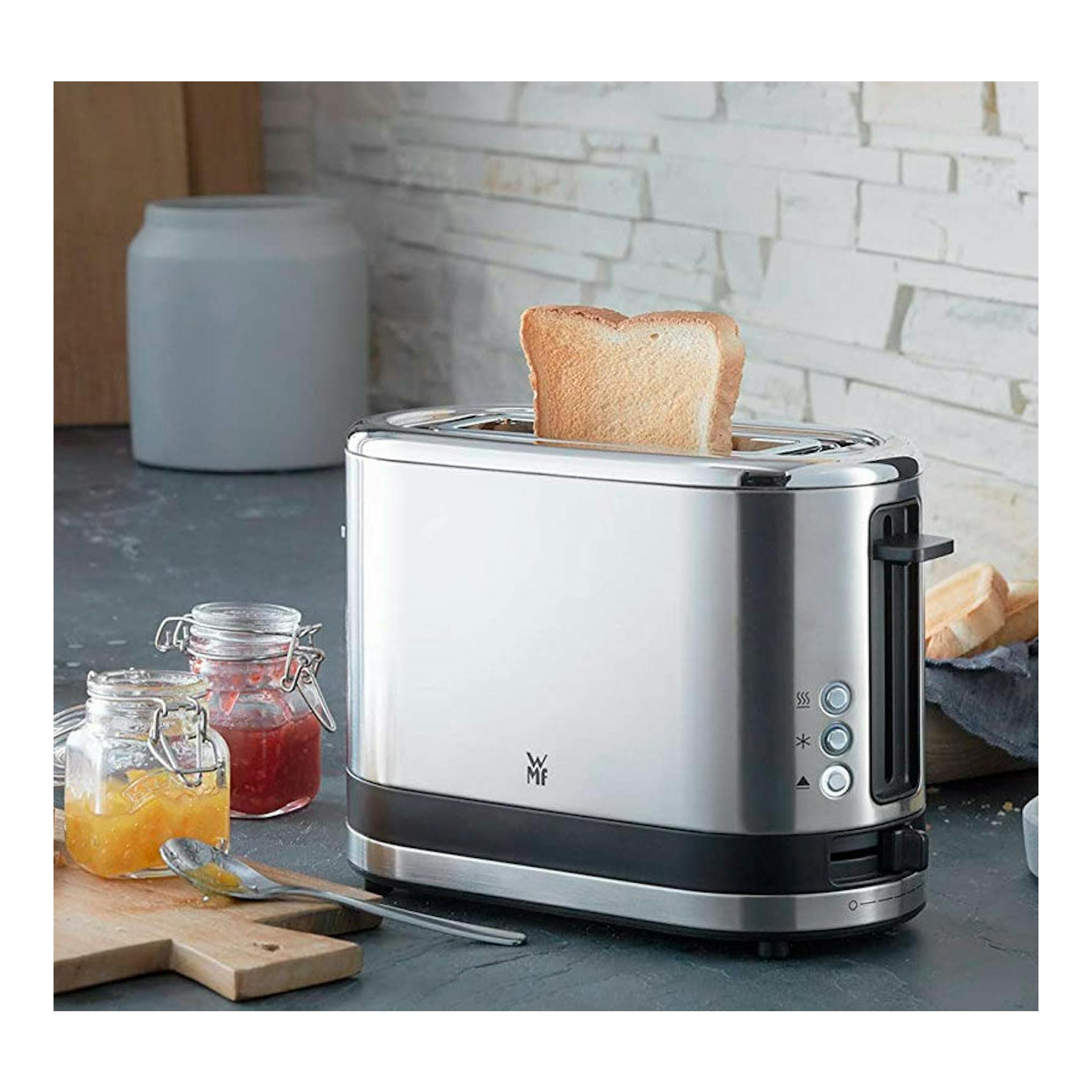 Tostador WMF Kitchenminis de 1 ranura, acero inoxidable, vista frontal con una rebanada de pan.