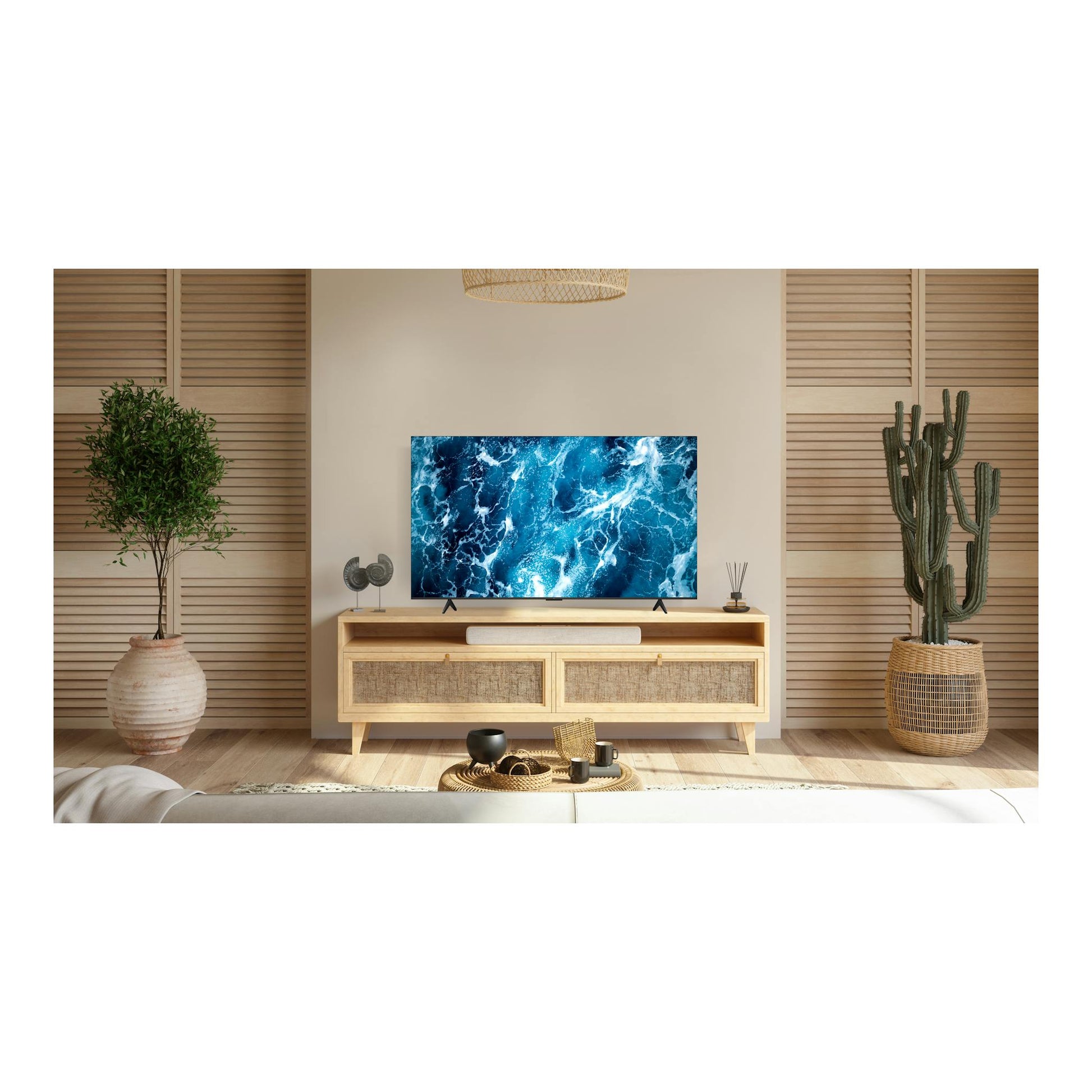 Televisor TCL 55T69C, vista frontal, pantalla con imagen azul sobre mueble de madera en un salón decorado.