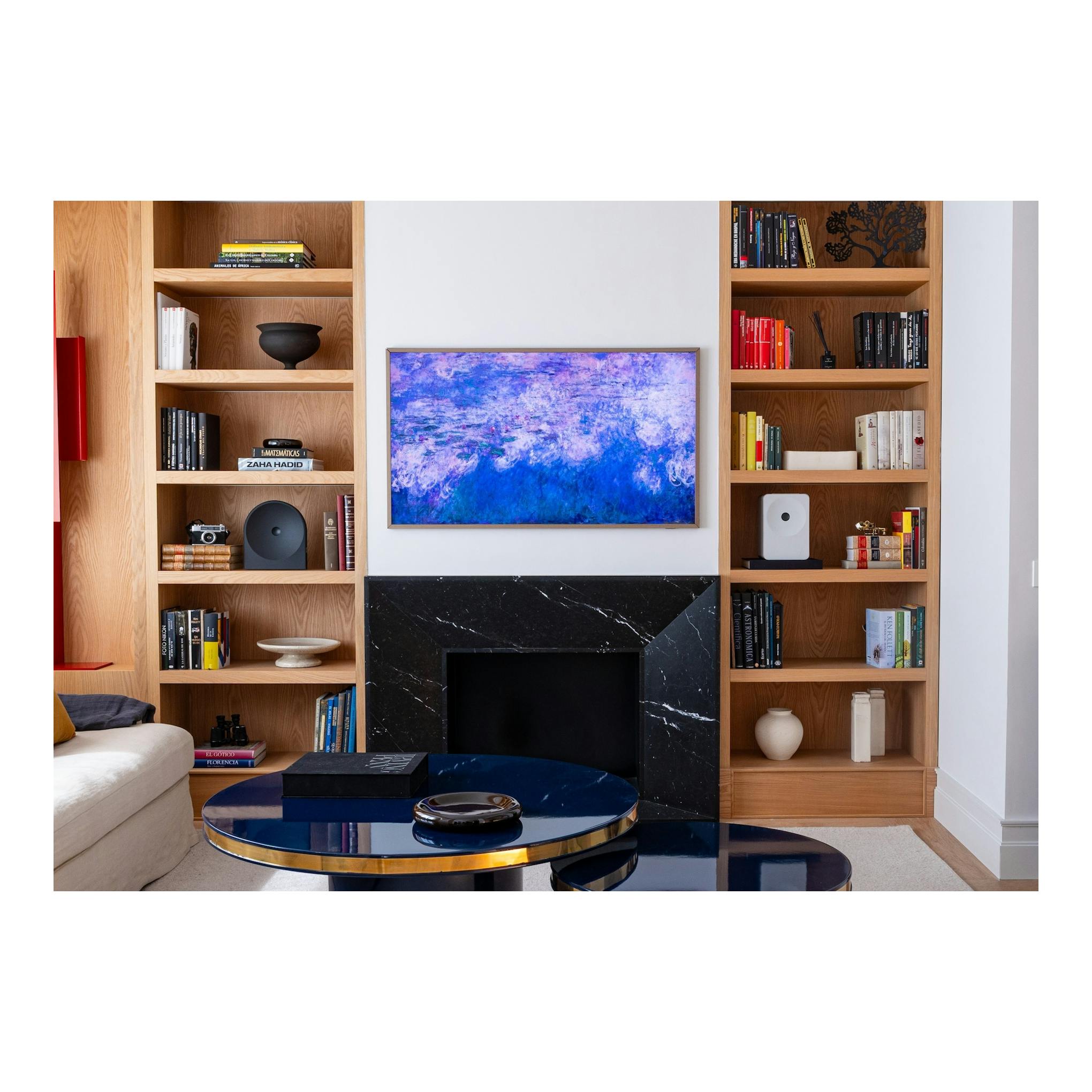 Televisor Samsung TQ85LS03HWUXXC montado en pared, vista frontal, con imagen abstracta azul y lila.
