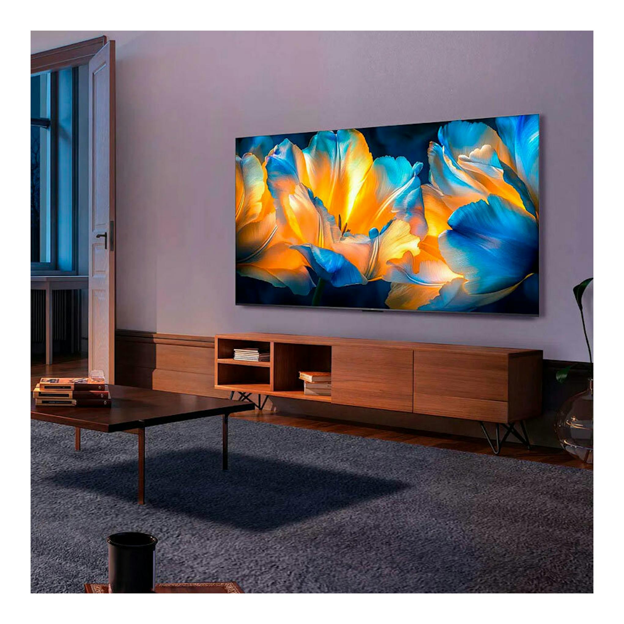 Televisor TCL 55C6K MiniLED 4K de 55 pulgadas, montado en pared, con imagen abstracta azul y naranja.